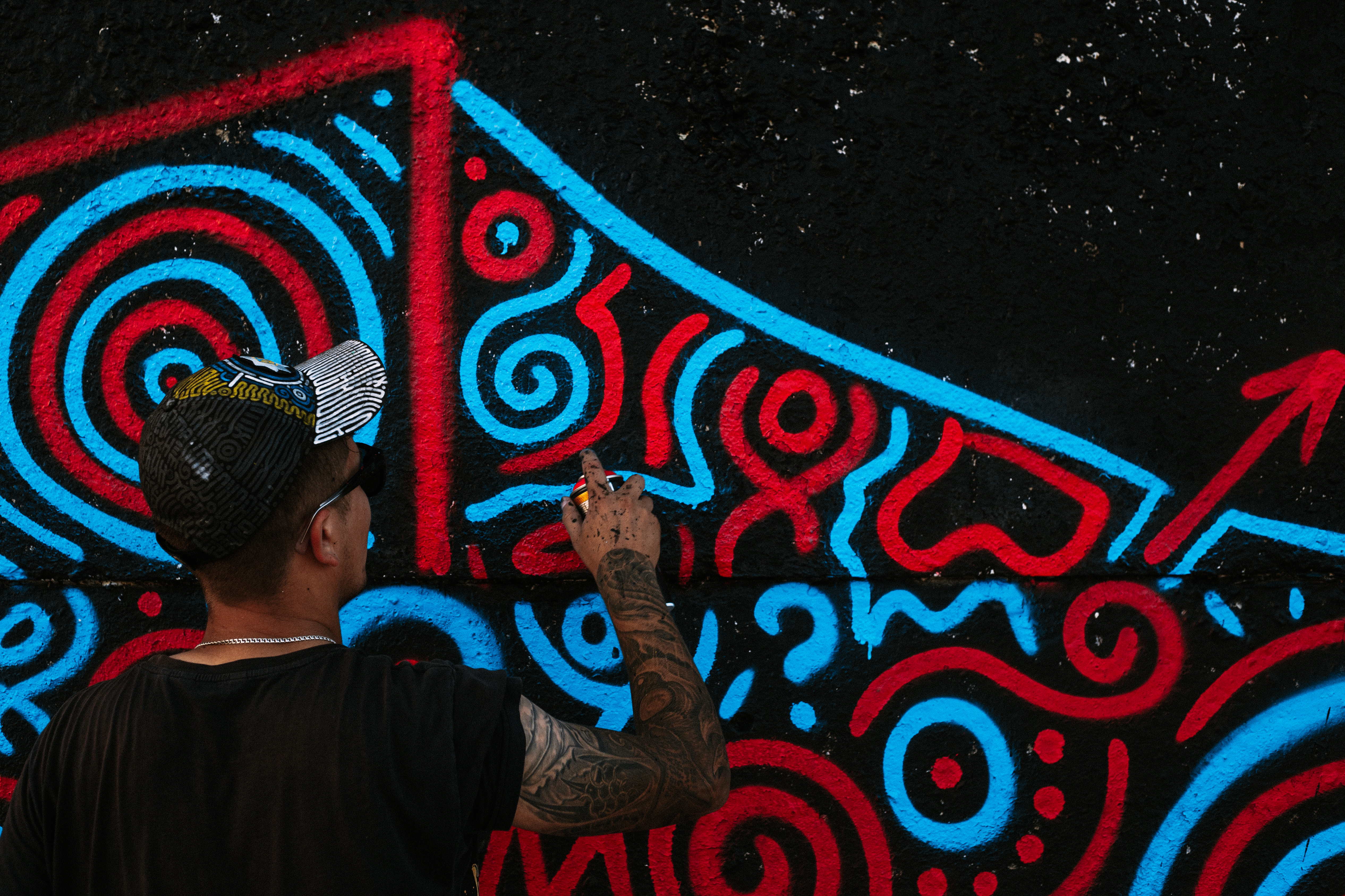 Графітчик розфарбовує стіну на фестивалі